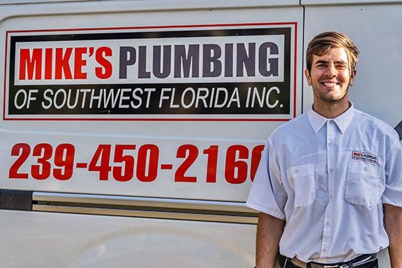 Plumber Standing By Mike's Plumbing of Southwest Florida Sign